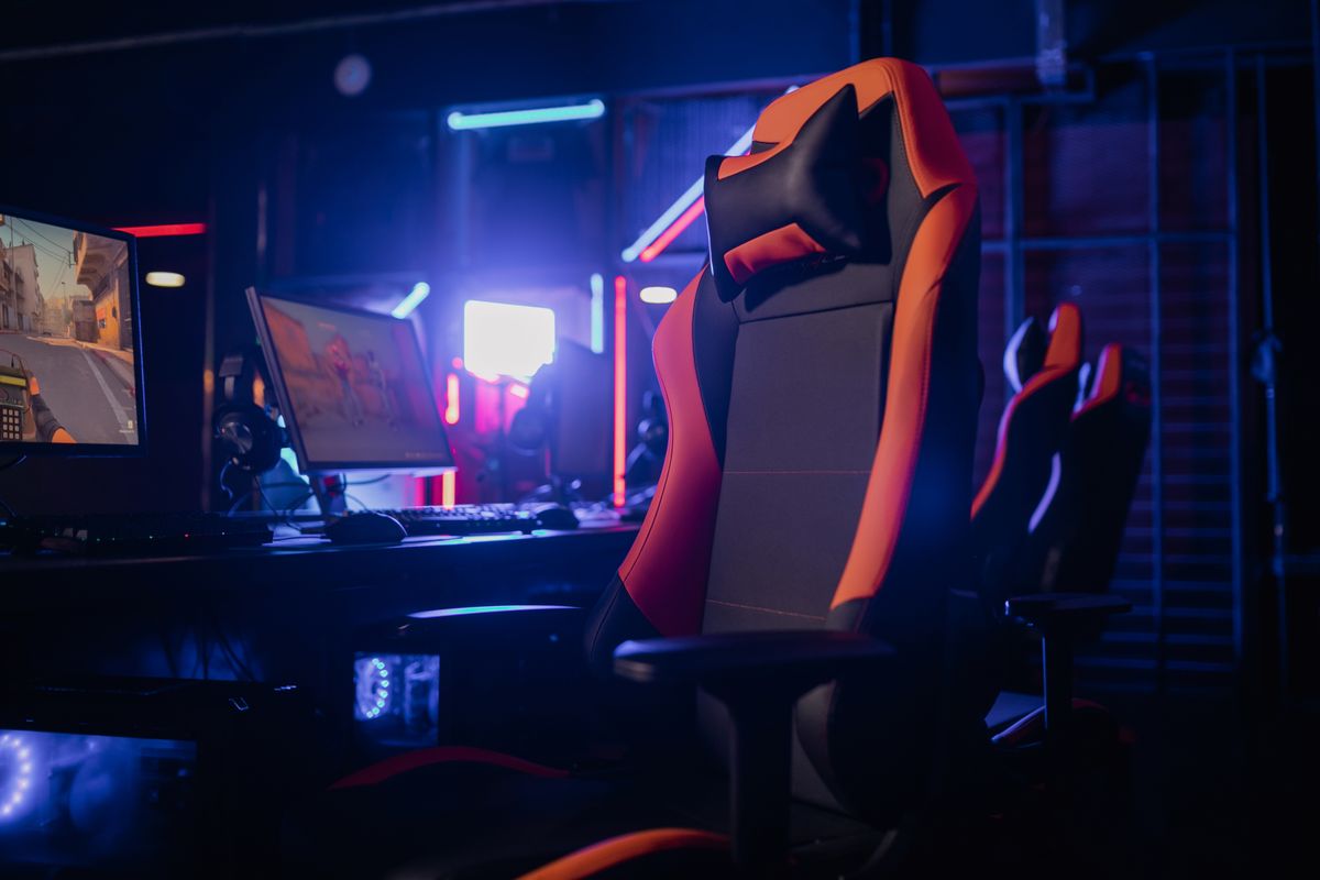 A gaming chair at a desk setup with dual monitors